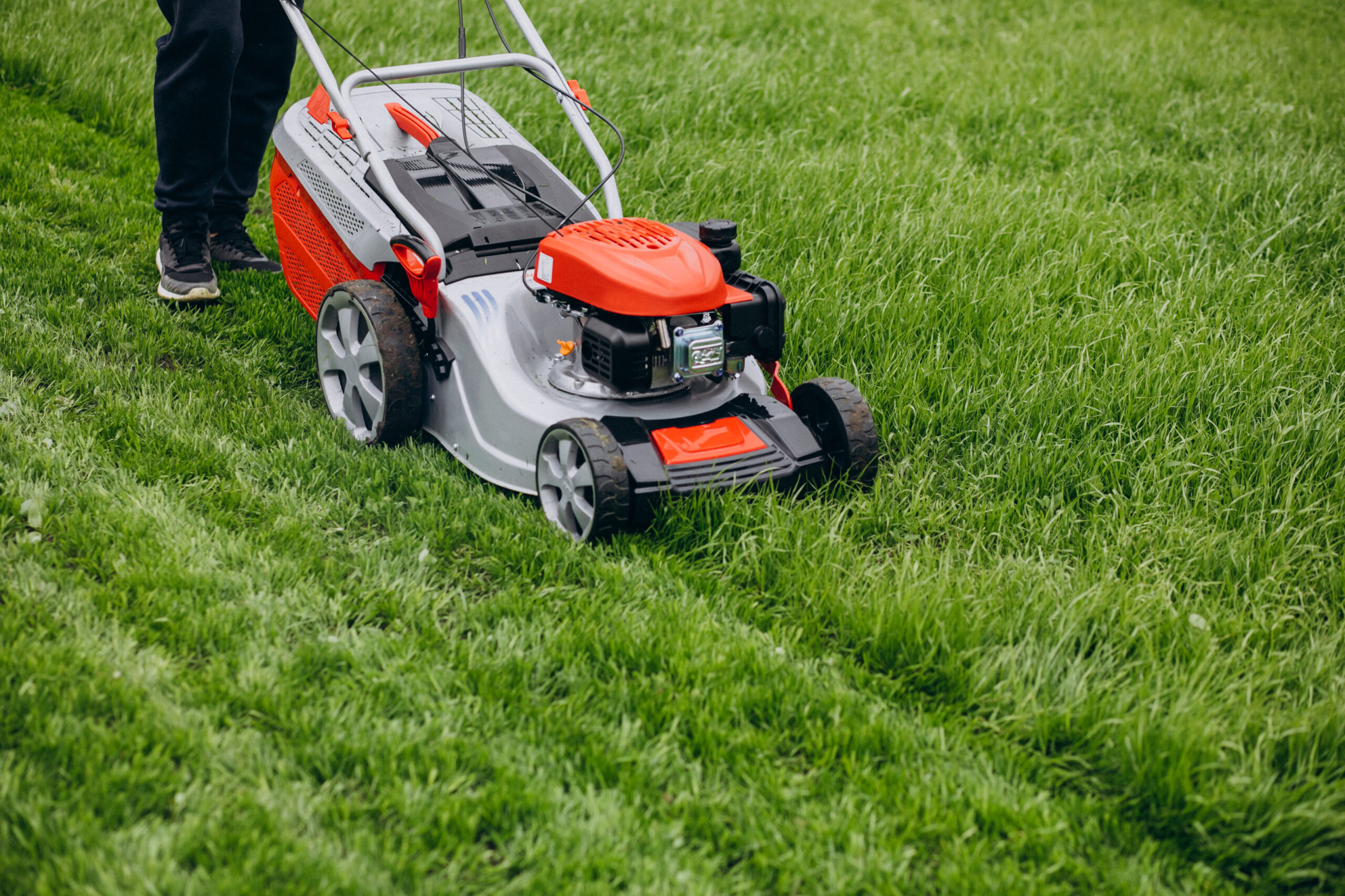 Man cutting grass with lawn mover in the back yard